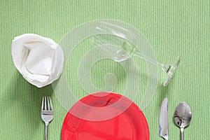 dinner place setting a red plate with silver fork and spoon on g