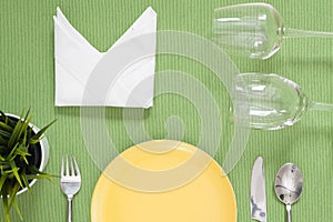 Dinner place setting a yellow plate with silver fork and spoon o