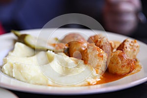 On dinner plate, mitbola mashed potatoes and pickled cucumber