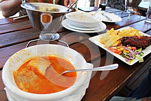 Dinner at restaurant - Hungarian fish soup named halaszle and fried hake with French fries and vegetables