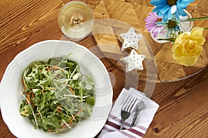 Dinner salad with wine on warm toned wood