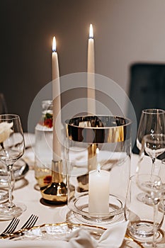 Dinner table adorned with lit candles and elegant glassware