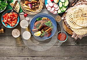 Dinner table with grilled sausage, tortilla, beer and different