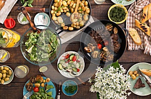 Dinner table with grilled steak, vegetables, potatoes, salad, sn