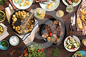 Dinner table with grilled steak, vegetables, potatoes, salad, sn