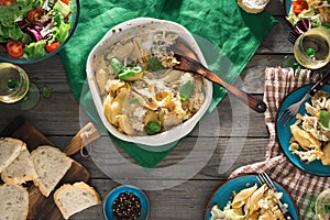 Dinner table with pasta, salad and wine on wooden table