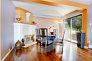 Dinning room with white fire place, hardwood floor, and orange i