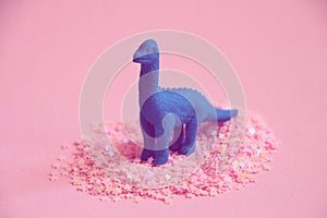 Dinosaur figure standing in pink party glitters