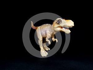 Dinosaur, plastic toy. The monster stands on his hind legs, his dreadful mouth with teeth. The background is black and uniform.