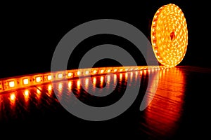 Diode decorative tape for lighting, a roll of LED strip with yellow warm light on the floor laminate