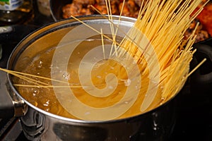 Dip spaghetti into boiling water in a saucepan. Pasta cooking