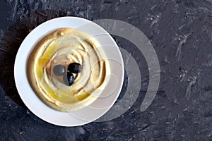 Dip Tahini with olives on dark gray background with copy space. Flat lay, top view. Tahina sauce.