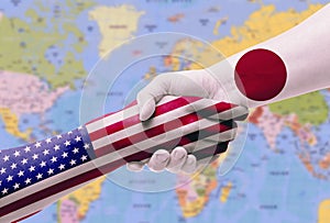 Diplomatic handshake between countries: flags of United States and Japan overprinted the two hands