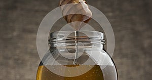 Dipping honey stick into the jar of honey.