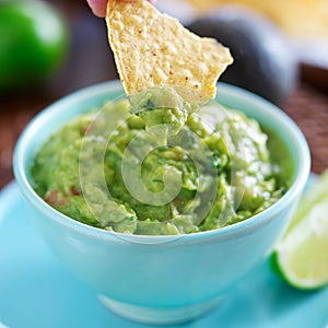 Dipping tortilla chip in mexican guacamole photo