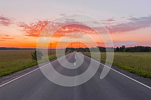 Direct asphalt road in the middle of a wheat field illuminated by a beautiful sunrise photo