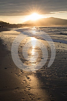 Direct golden sunset`s sunlight on a scenic sandy beach in hendaye in dramatic cloudy atmosphere, basque country, france