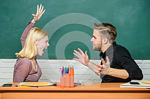 Direct opposition. Couple arguing in classroom. Angry woman going to man with her fists. Teacher and schoolmaster are at