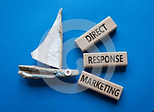 Direct Response Marketing symbol. Concept words Direct Response Marketing on wooden blocks. Beautiful blue background with boat.