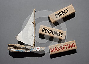 Direct Response Marketing symbol. Concept words Direct Response Marketing on wooden blocks. Beautiful grey background with boat.