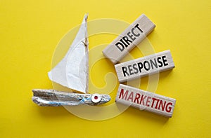 Direct Response Marketing symbol. Concept words Direct Response Marketing on wooden blocks. Beautiful yellow background with boat