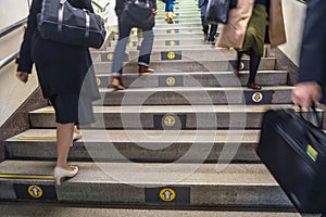 Direction arrows on steps on Tokyo subway with commuters, Tokyo