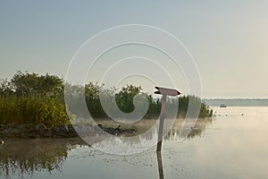 A directional lake channel marker at sunrise