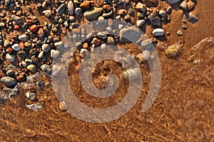 Directly Above Flatlay of Gentle Waves Lapping Sand and Pebble Beach with Pristine Clear Cool Water