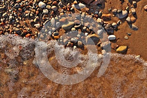 Directly Above Flatlay of Gentle Waves Lapping Sand and Pebble Beach with Pristine Clear Cool Water