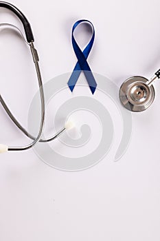 Directly above shot of stethoscope with blue stomach cancer awareness ribbon on white background