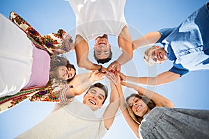 Directly below shot of friends huddling with arms raised