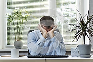 Director in his office rubs eyes wearily. Young man sits at the workplace and rubs his eyes. Work in the office and eye problem