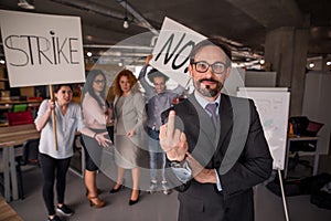 Director showing long finger, employees holding posters with words strike and no.