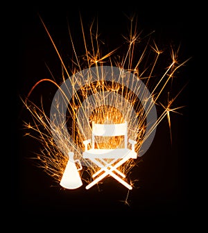 Directorâ€™s chair and megaphone in glowing sparkler on dark background