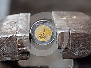 Dirham coin clamped in a metal vise. Currency and United Arab Emirates economy under the onslaught