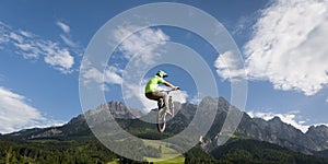 Dirt biker jumps high up in the air with mountains