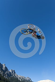 Dirt biker makes a high backflip with blue sky