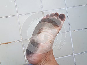 Dirt on bottom of foot and toes with white tile floor