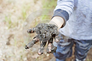 DIRT CHILD HAND PLAYING A MUD PUDDLE OUTDOORS