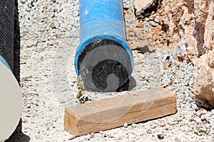 Dirt covered dilapidated partially rusted old blue metal pipe closed with black plastic plug at local construction site