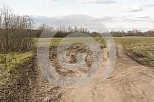 Dirt damaged rural spring road in a field. concept of problem with the roads