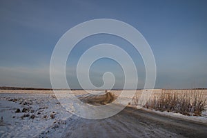 Dirt frozen uneven road stretches through many kilometers of snow