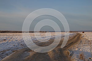 Dirt frozen uneven road stretches through many kilometers of snow