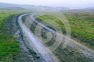 dirt muddy road wet Puddle countryside autumn fall green grass steppe after rain Tire tracks beautiful landscape Moldova