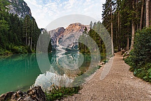 Dirt path runs along Lake Braies under a cloudy sky