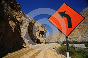 Dirt road in the Andes of Peru without people and Te transito sign with curve and blue sky