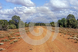 Dirt road in Australian outback scene with clouds