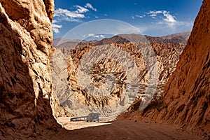 Dirt road with car passing through the Quebrada de las Flechas in Argentina photo