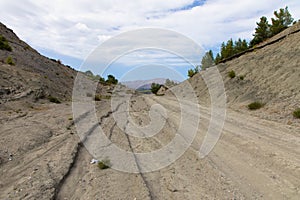 Dirt road with car tracks in desert greek landscape.