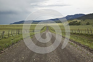 Dirt road into Centennial Valley, Montana with incoming storm, green fields and mountains photo